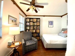 Relax in this inviting bedroom with a large bed, comfortable seating area, and bookshelf.