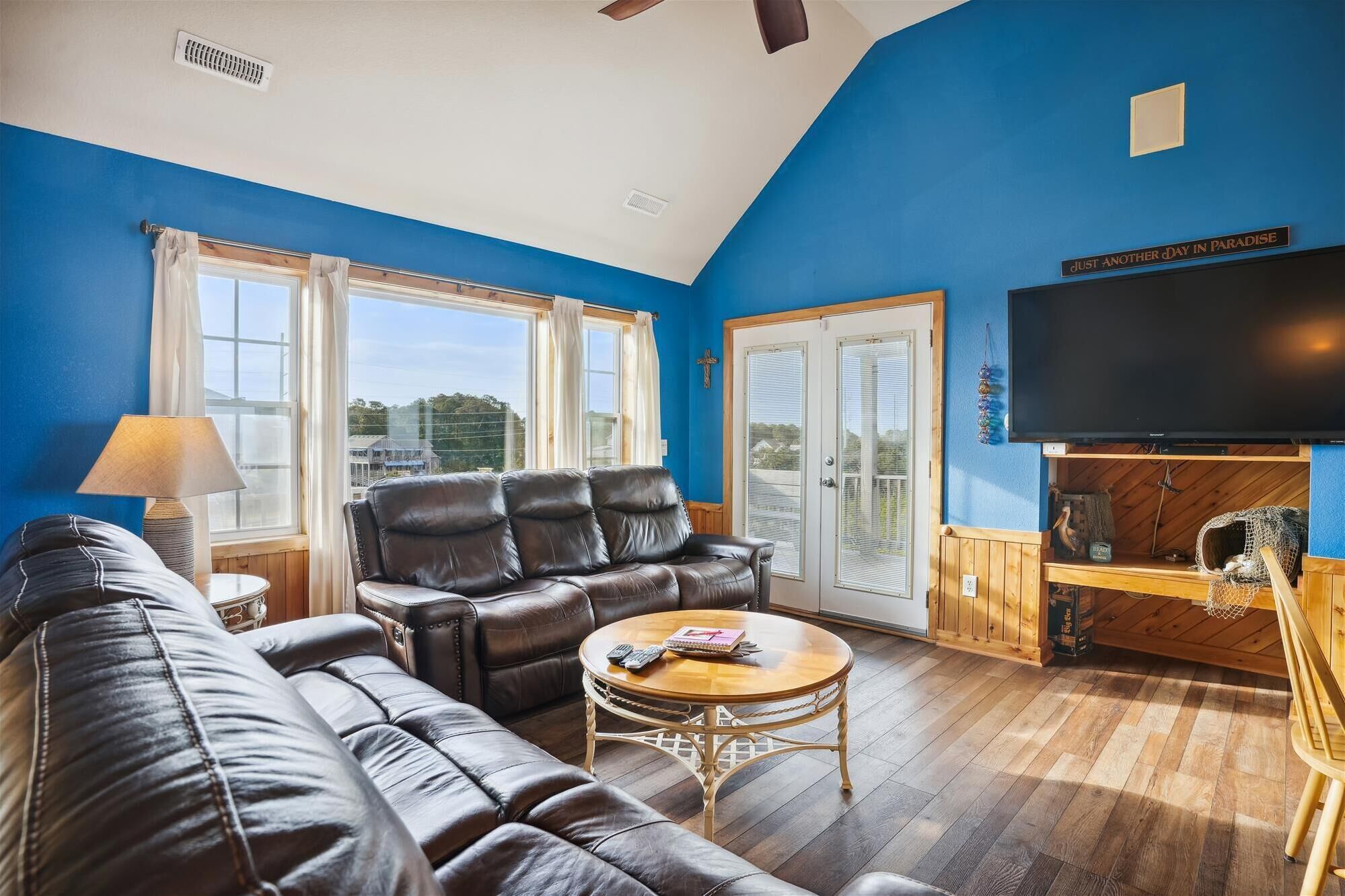 A living room with a blue wall, a leather sofa, a wooden coffee table, and a television.