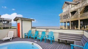 A wooden deck with a pool, blue Adirondack chairs, and a red door. - 7130- Sunset Breeze - Soundfront Waves | Pool & Sunset Views (Waves)