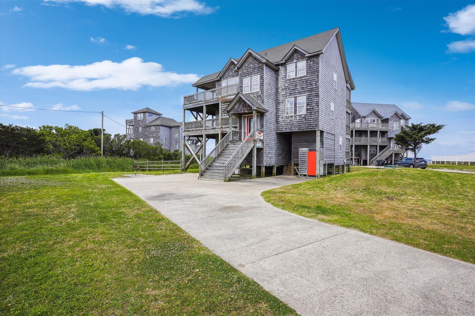 A multi-story building with a wooden exterior, a central staircase, and a small deck area.