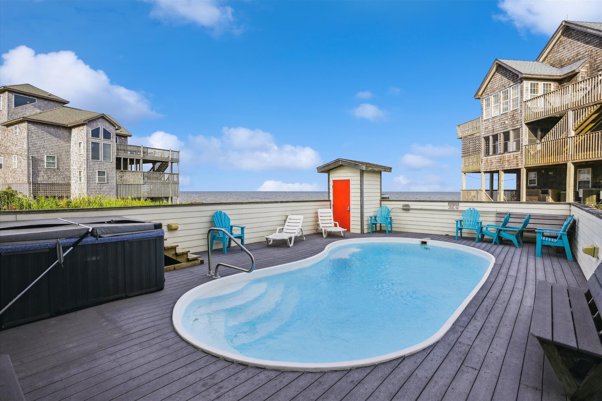 Une terrasse en bois avec une piscine, des chaises longues et un jacuzzi.