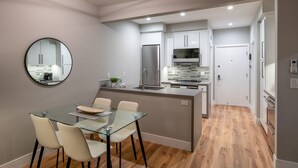 A modern kitchen with a central island, a dining area with a glass table, and a round mirror on the wall. - 645 Fresh Modern Condo Inside Resort Gates - Free Wifi - Walk to Spa (Carlsbad)