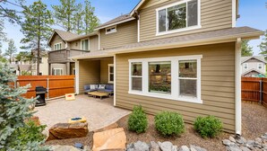 A two-story house with a covered patio area, a barbecue grill, and a fenced backyard. - Pinnacle Pines | Forest Views | Modern Home with EV Charger | Direct Trail Access (Flagstaff)