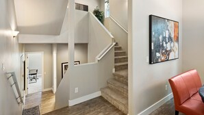 A modern interior with a staircase, a dining area, and a red chair. - Pinnacle Pines | Forest Views | Modern Home with EV Charger | Direct Trail Access (Flagstaff)
