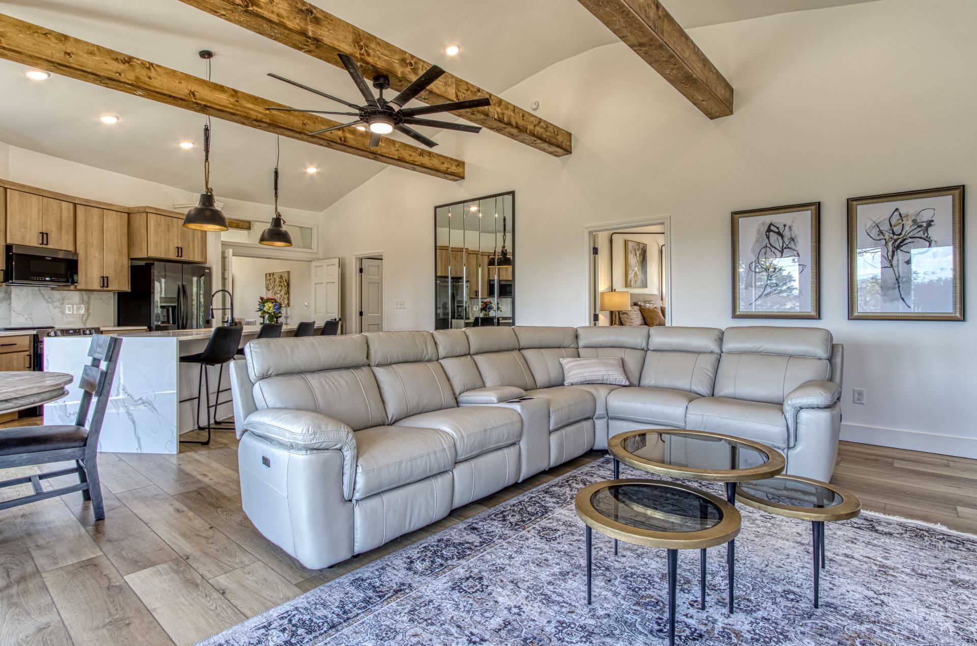 A spacious living area with a large L-shaped leather sofa, a dining table with chairs, and a kitchen in the background.