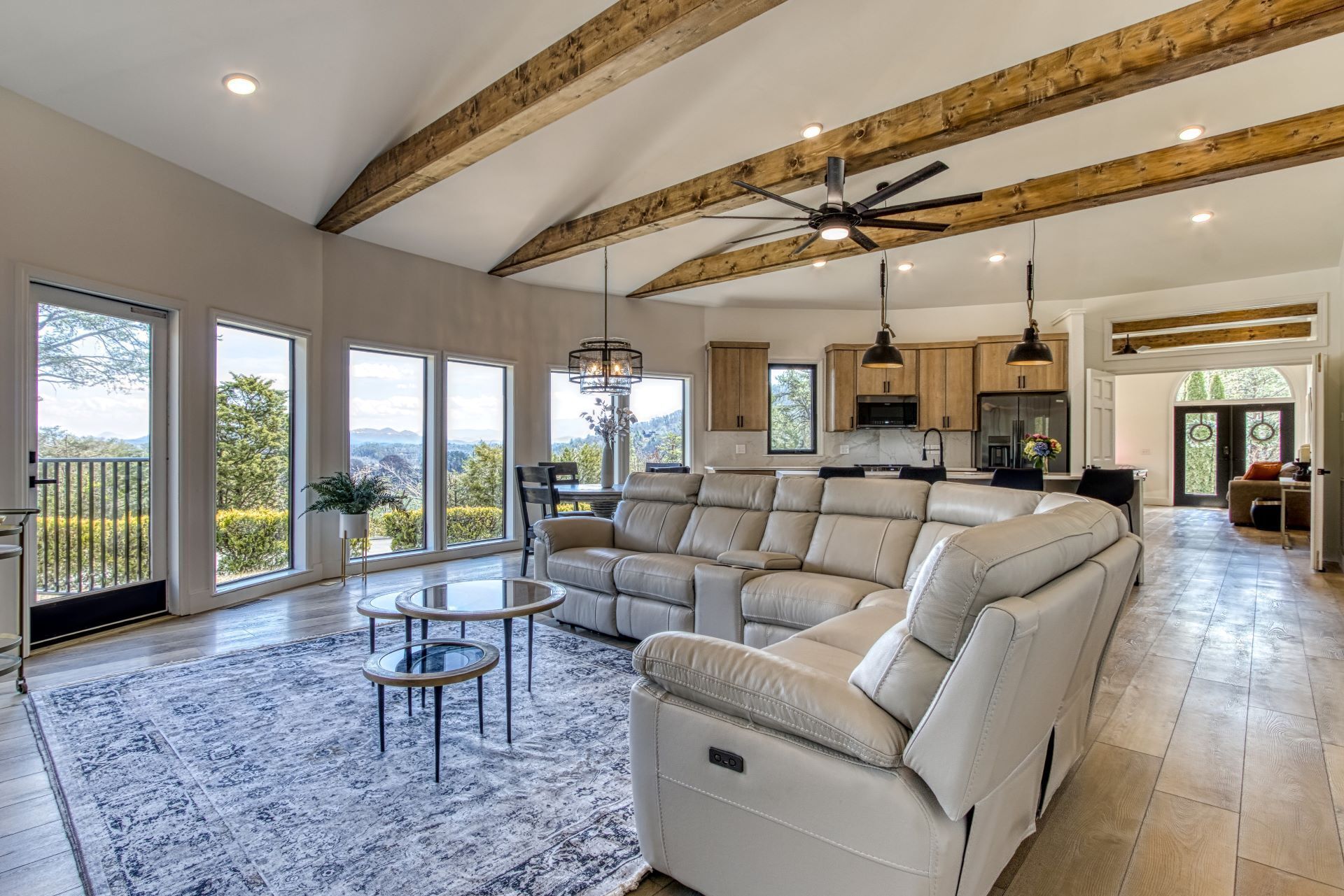 A spacious living area with a large sectional sofa, a glass coffee table, and a ceiling fan.