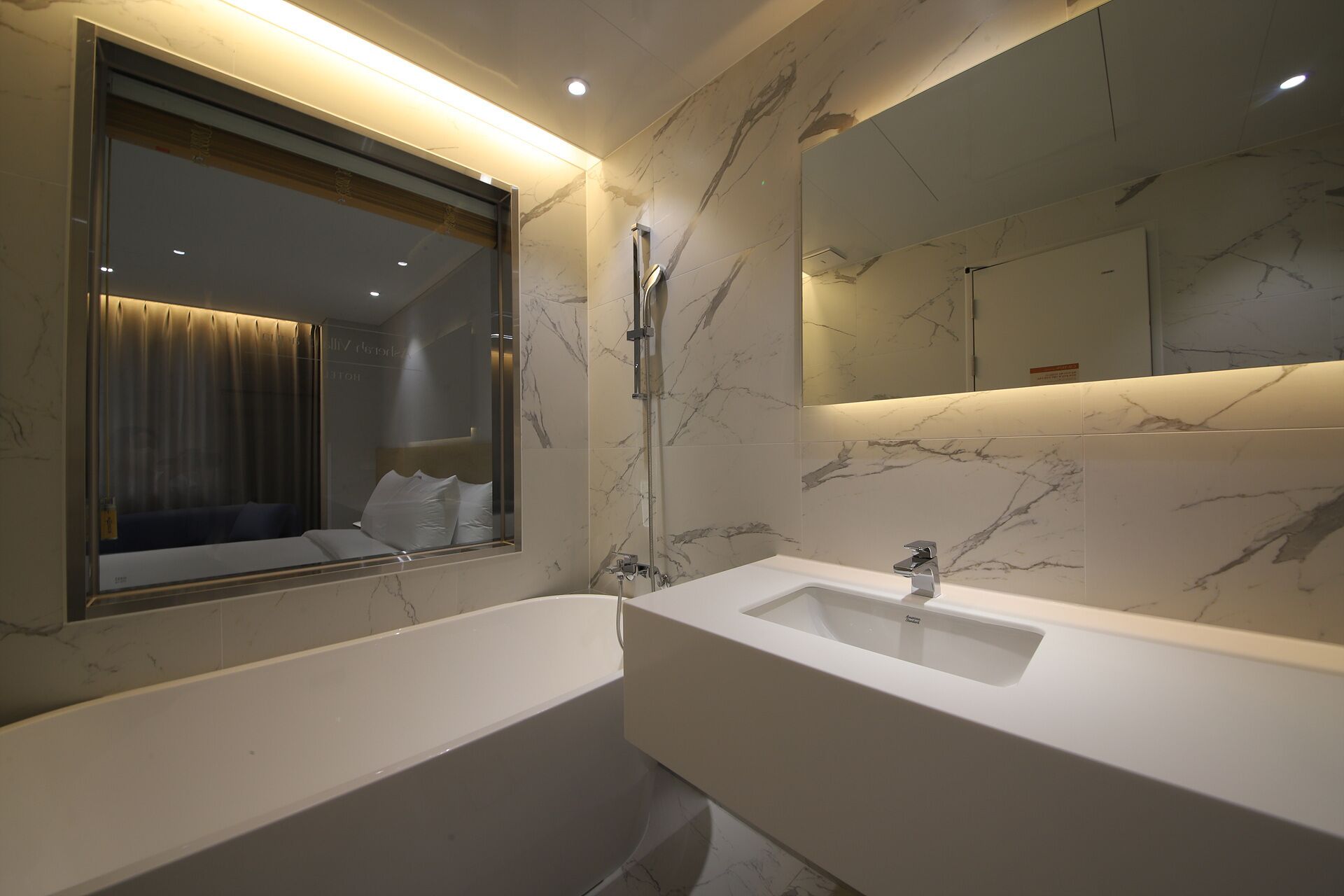 Ein modernes Badezimmer mit einem großen Spiegel, einer Badewanne und einem Waschbecken.