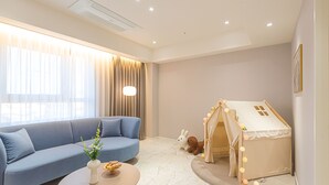 Un salon moderne avec un canapé bleu, une table basse ronde et une maisonnette pour enfants avec des lumières.