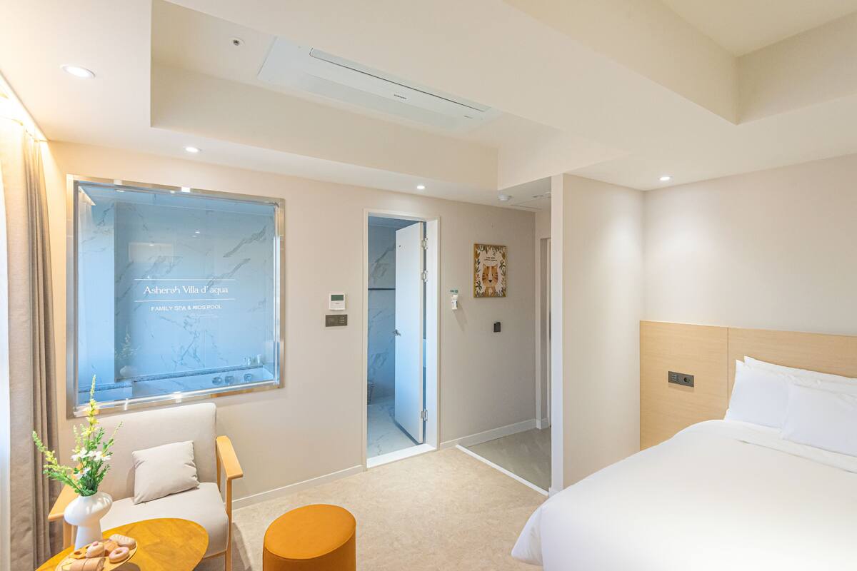 Ein Hotelzimmer mit Bett, Sofa, kleinem Tisch und einem durchgegangenen Tür erkennbaren Badezimmer.