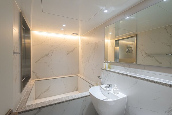 Une salle de bain moderne avec un lavabo en marbre, une baignoire et un grand miroir.