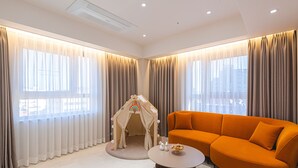 Un salon moderne avec un canapé beige, une table basse ronde et une maisonnette pour enfants.