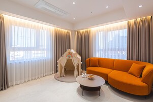 Una sala de estar moderna con un sofá color beige, una mesa de centro redonda y una casita de juegos para niños.