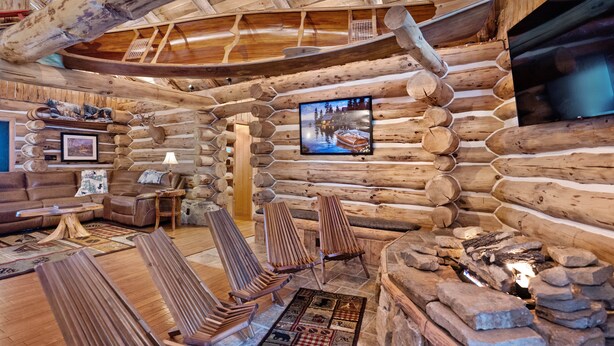 L’intérieur d’une cabane en rondins, avec une cheminée, des meubles en bois et un téléviseur fixé au mur.