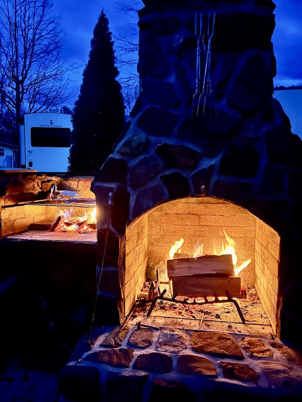 A stone fireplace with a fire burning inside, surrounded by a stone structure.