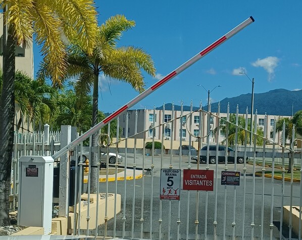 A gated entrance with a speed limit sign, a warning for children playing, and a sign indicating visitor entry. - Miradores Del Yunque Rio Grande Piscina (Río Grande)