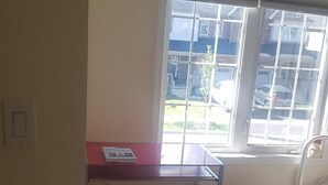 A room with a desk, chair, and a window with a view of a street and parked cars.