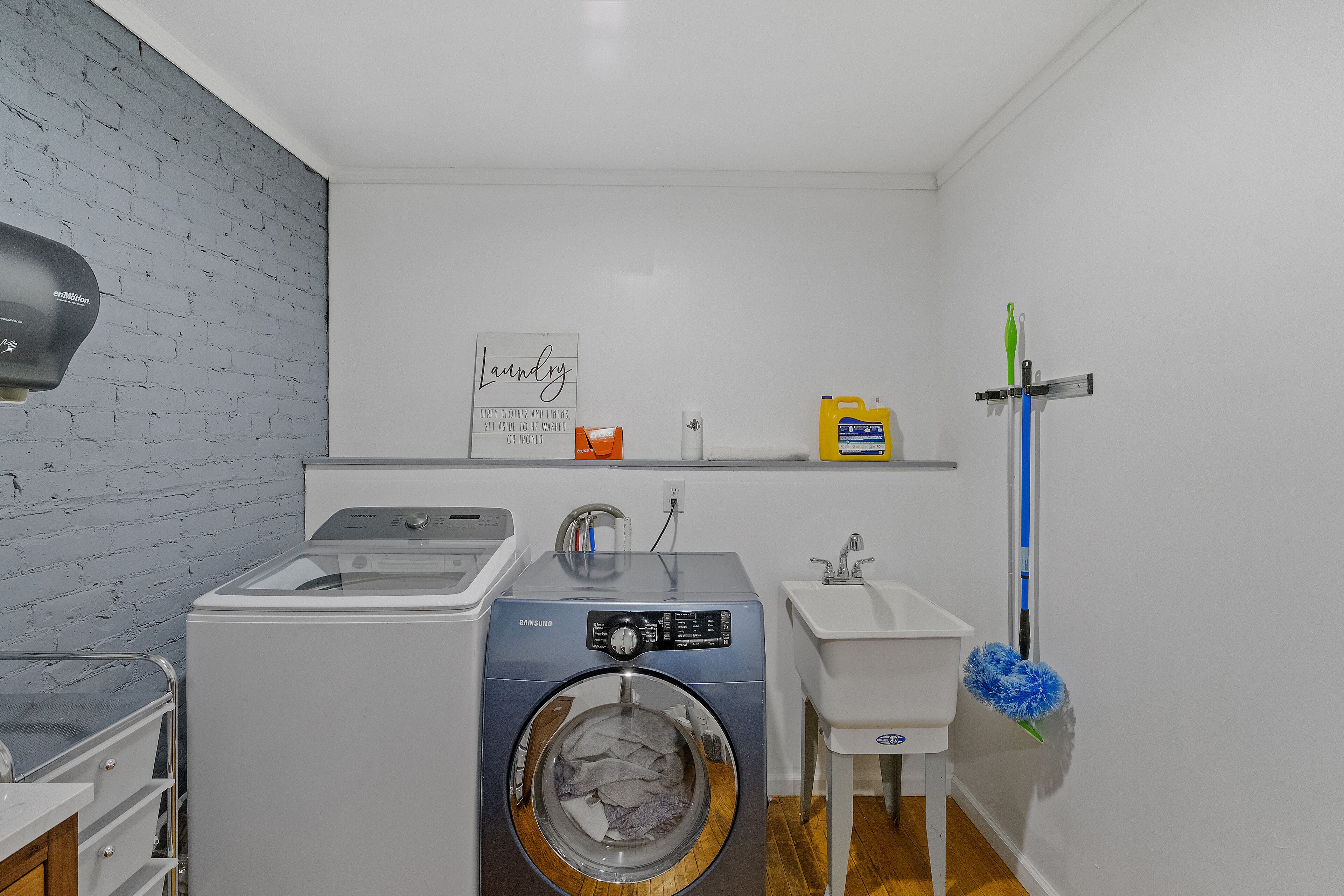 Un espacio para lavandería con lavadora, lavabo y estante con productos de limpieza.