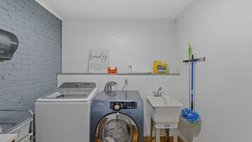 Un espacio para lavandería con lavadora, lavabo y estante con productos de limpieza.