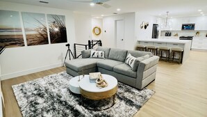 A modern living room with a grey sectional sofa, a round coffee table, and a black-and-white rug.