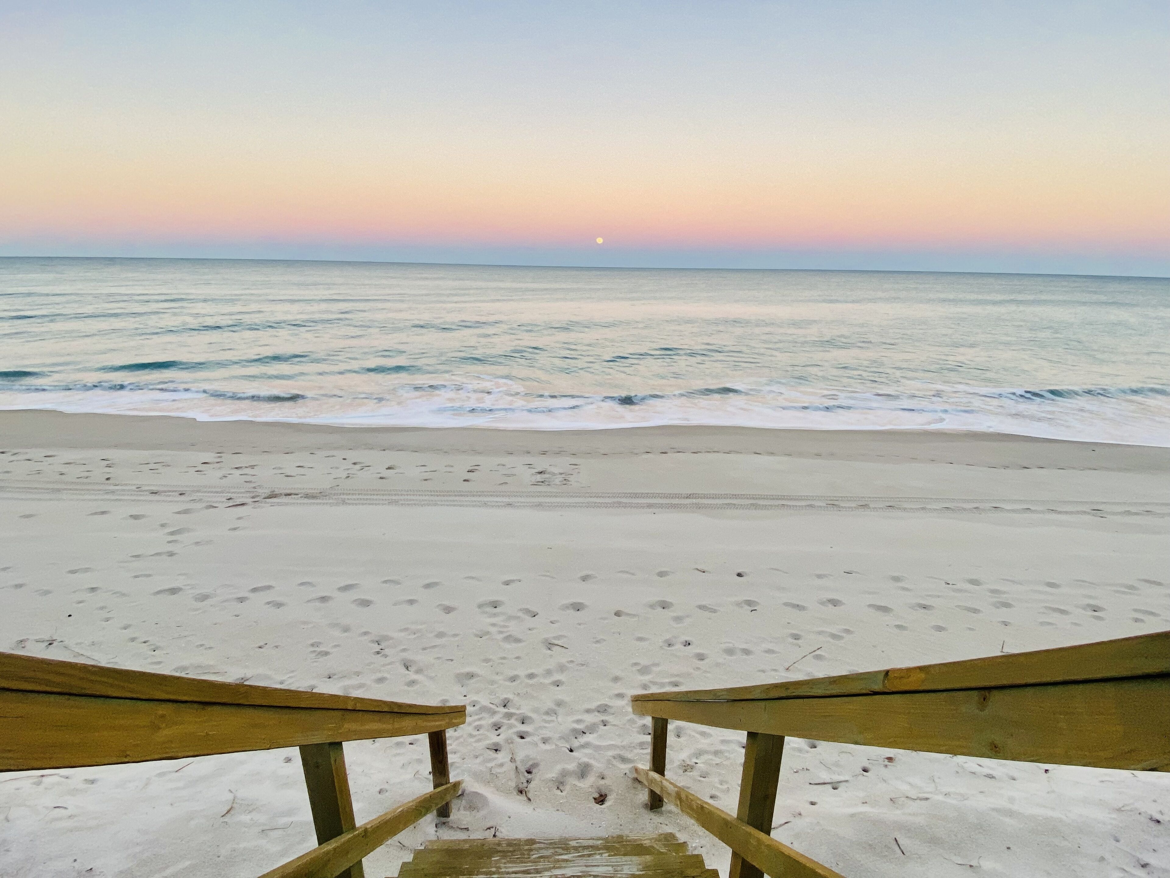 A beach with a wooden walkway leading to the water.