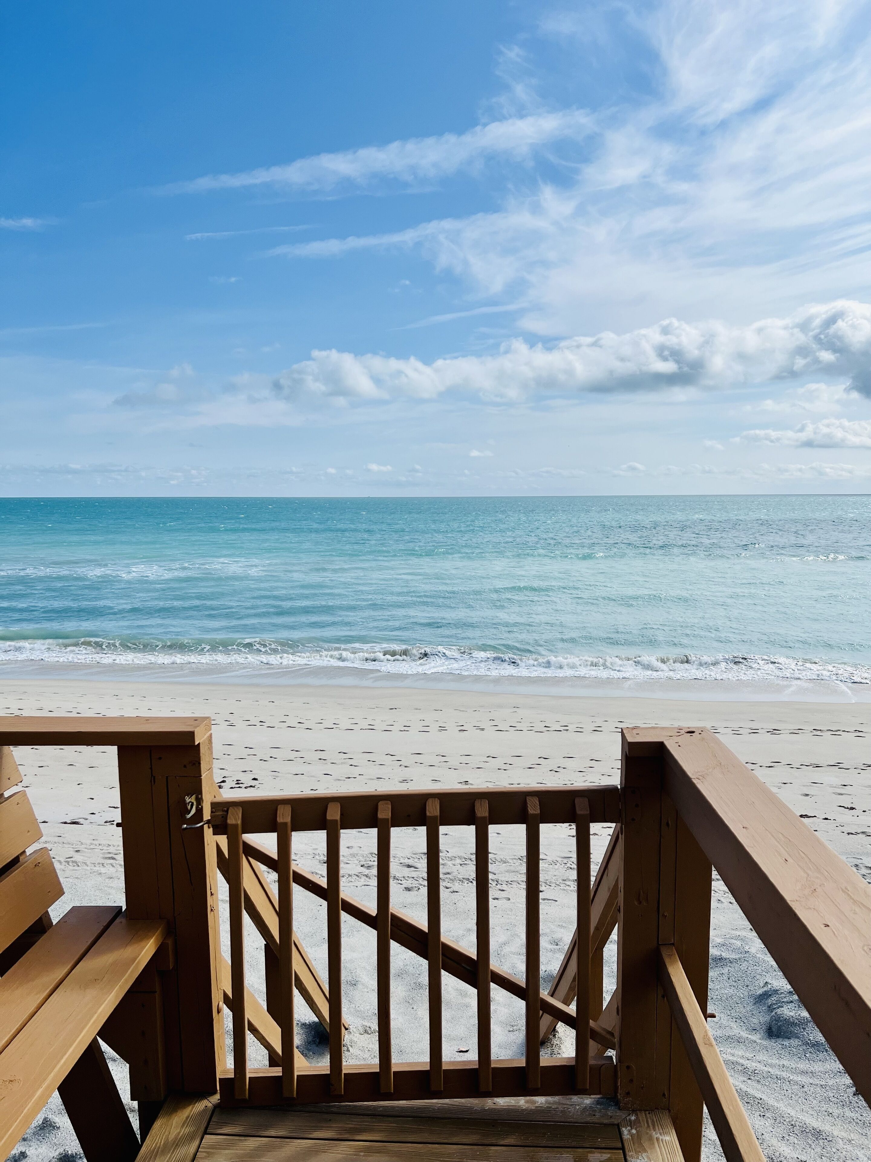 A wooden beach deck with a view of the ocean.