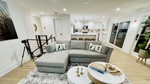 A modern living room with a grey sectional sofa, a round coffee table, and a black and white rug.