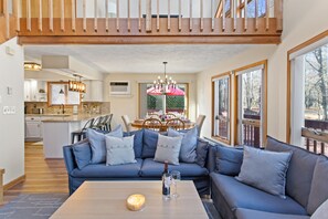 A modern living room with a blue sectional sofa, a wooden coffee table, and a dining area in the background. - •Redwoods Chalet in the Poconos• (Albrightsville)