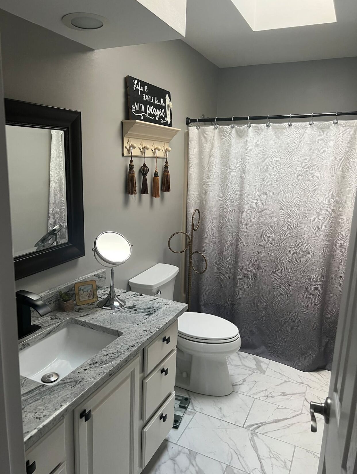 Un baño con tocador, lavamanos, espejo, inodoro y cortina de ducha.