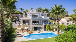 A multi-story house with a swimming pool, surrounded by palm trees and greenery. - 5 Star Villa Cyclamen – Luxury Pools & Spa (Algarve)
