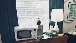 A hotel room with a wooden dresser, a microwave, a coffee maker, a lamp, and a window with curtains. - Spacious guesthouse located in the heart of Weatherford. (Weatherford)