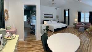 A hotel room with a bed, a round dining table, a sofa, and a small table with a lamp. - Spacious guesthouse located in the heart of Weatherford. (Weatherford)