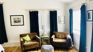 A living room with two armchairs, a small table with a lamp, and a window with curtains. - Spacious guesthouse located in the heart of Weatherford. (Weatherford)