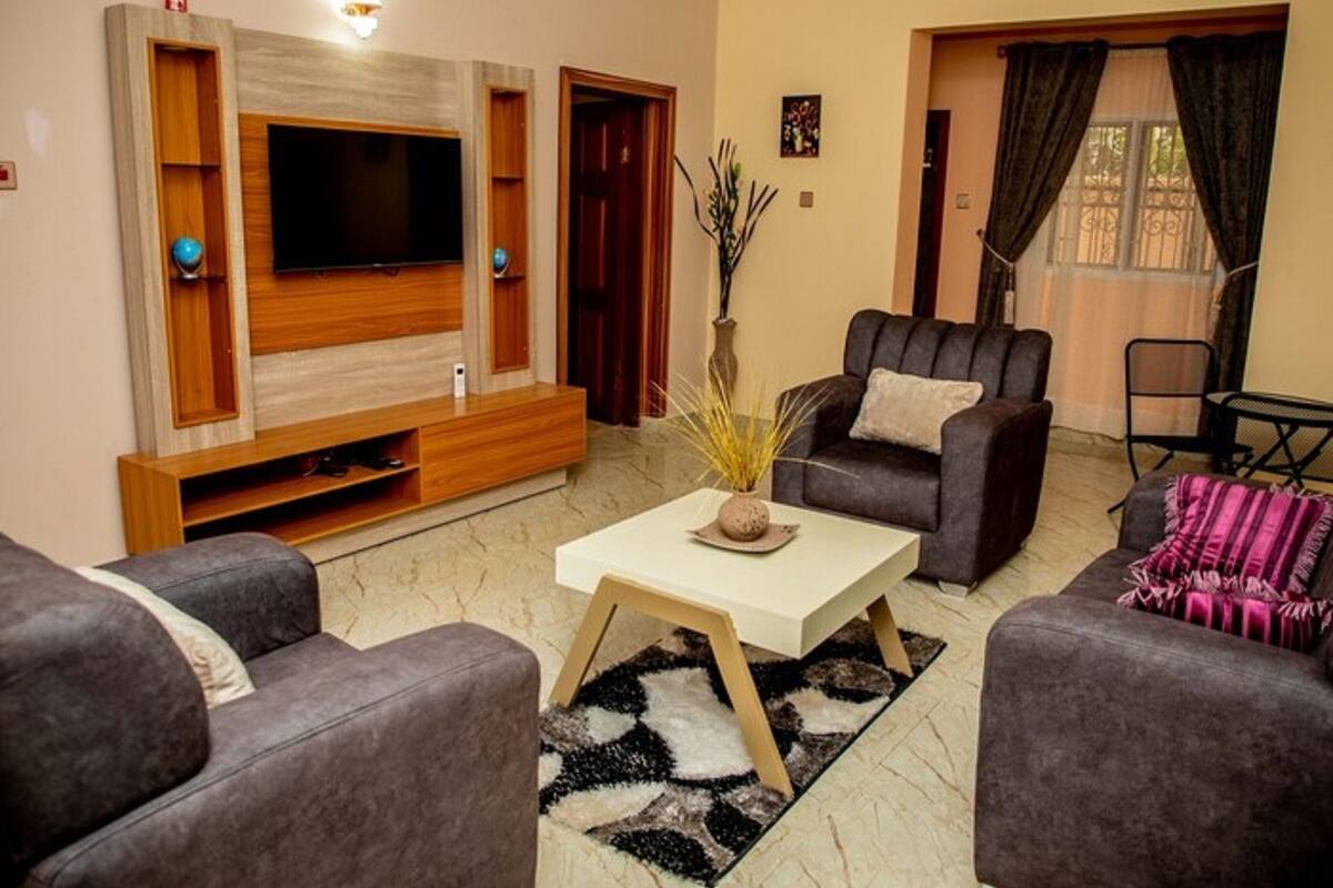 A living room with a flat-screen TV, two sofas, a coffee table, and a decorative vase.