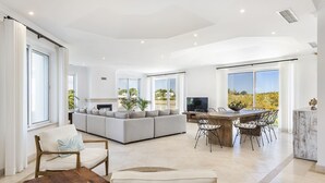Amplia sala de estar con un sofá grande, una mesa de comedor con sillas y un televisor.