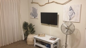 A living room with a flat-screen TV, a standing fan, a small table with a magazine, and a potted plant. - Private guest suite on the North Shore (Auckland)
