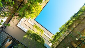 A modern building with a clear blue sky, a swimming pool, and greenery. - Tanaga Coliving (Seminyak)