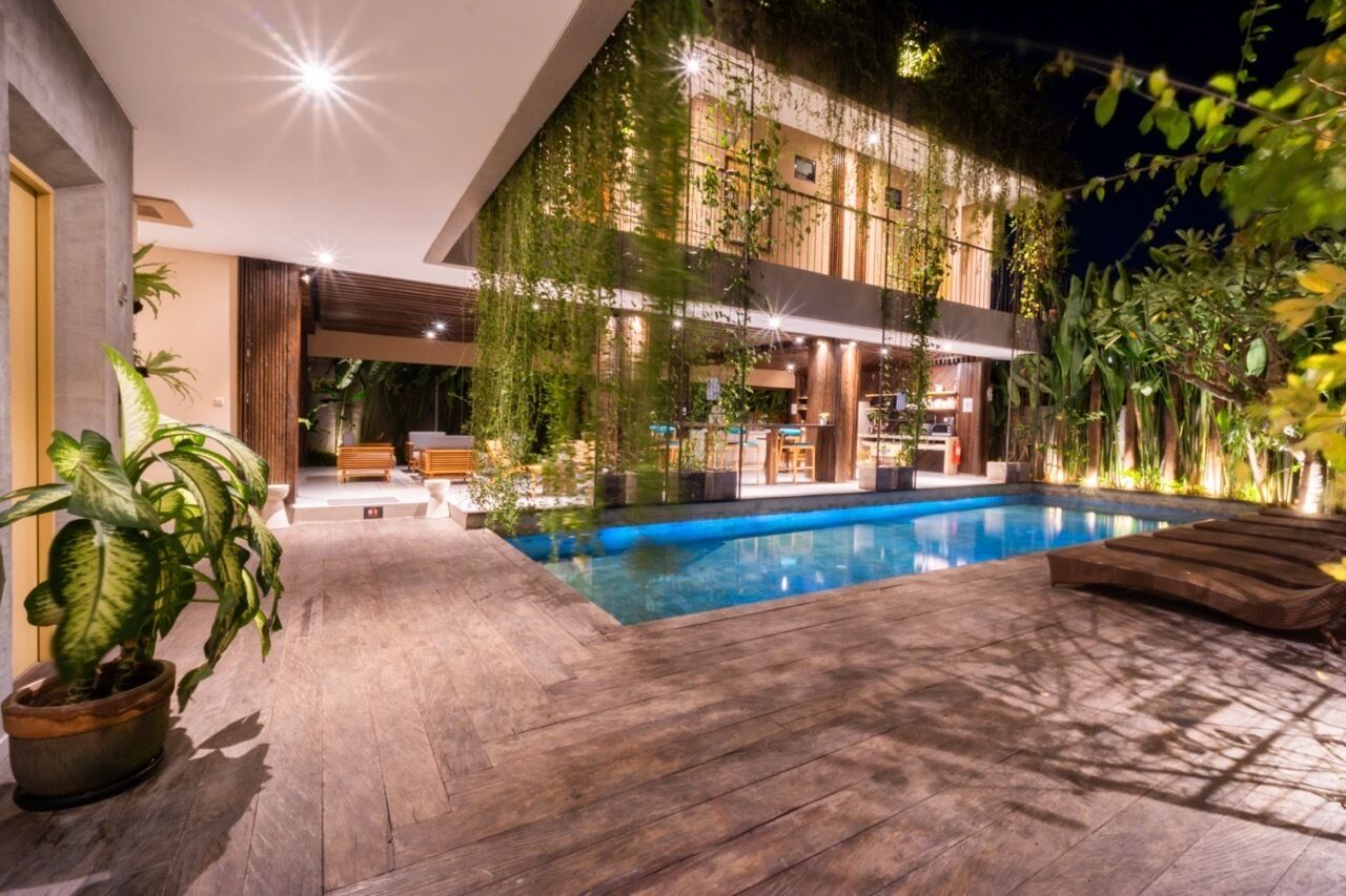Un edificio moderno con piscina, terraza de madera y plantas en macetas.