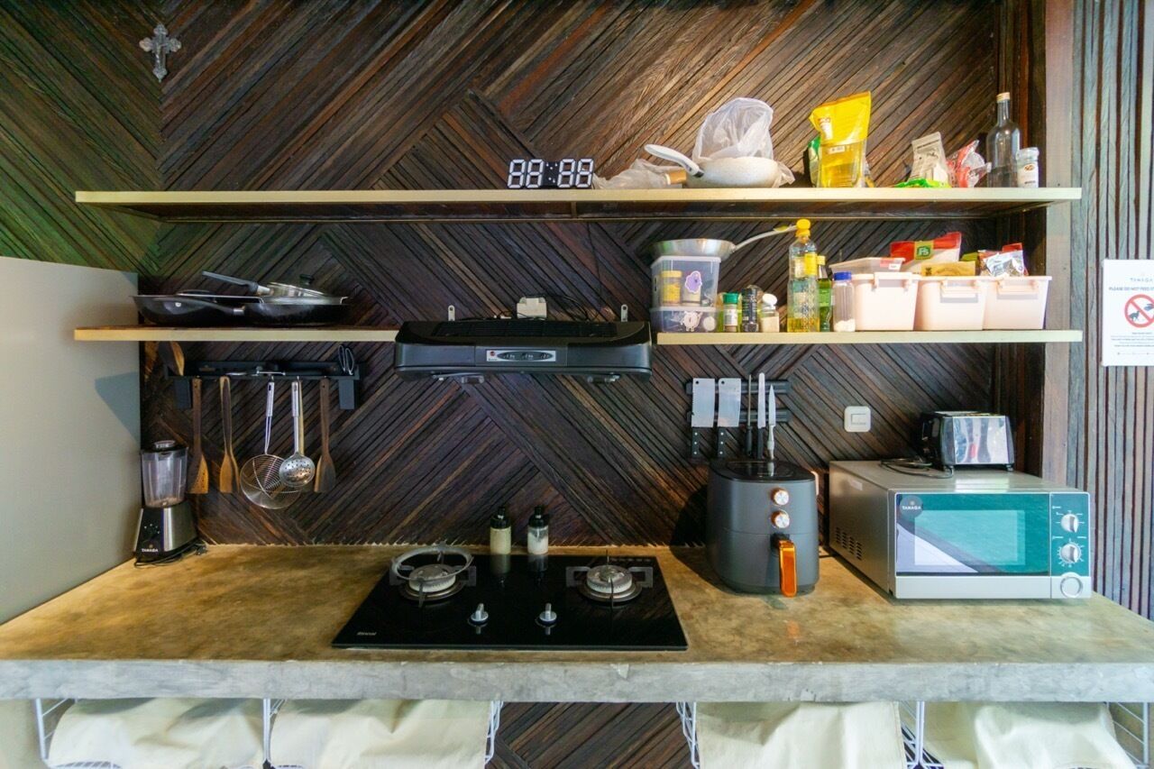 A kitchen with a herringbone-patterned wall, a digital clock, and various kitchen appliances and utensils.