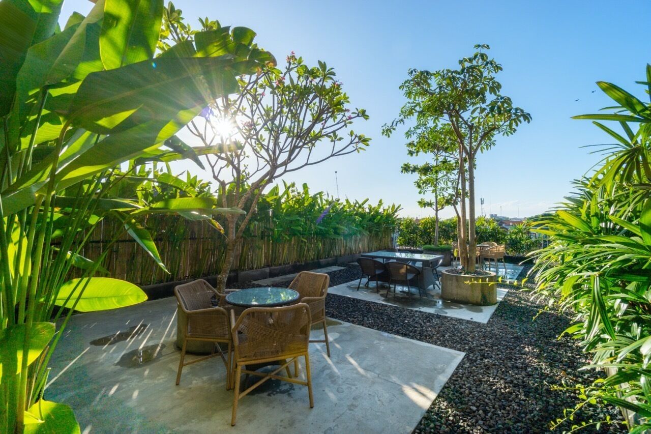 An outdoor patio with a dining area, a hot tub, and a bamboo fence.