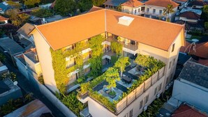 A multi-story building with a rooftop garden and outdoor seating area. - Tanaga Coliving (Seminyak)