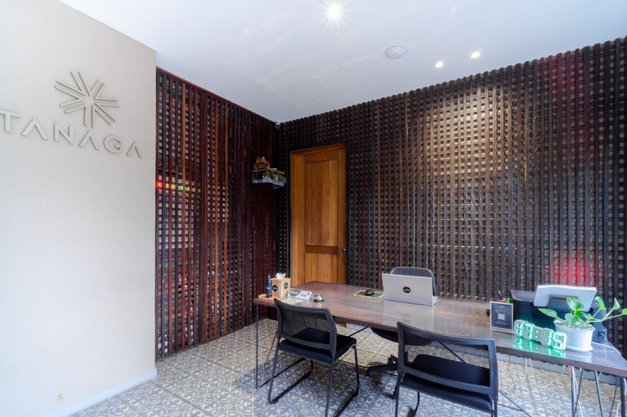 Una sala de conferencias con una mesa de madera, cuatro sillas, una computadora portátil, una máquina de café y una planta en maceta.