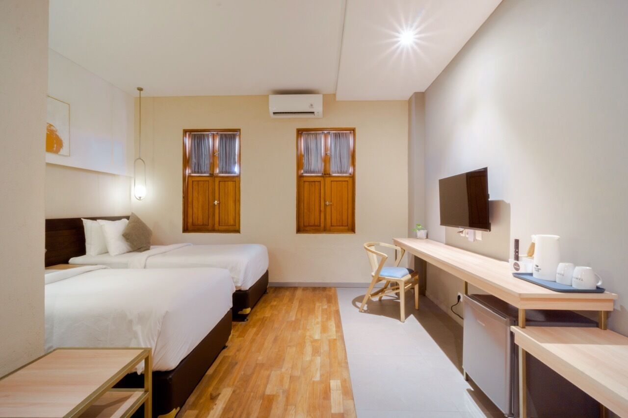 Una camera d'albergo con due letti, una scrivania, una sedia, una TV e un angolo cottura.