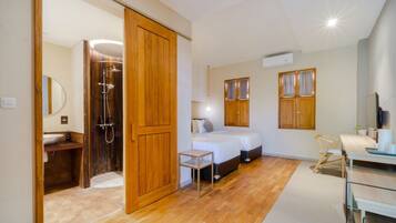 Een kleine slaapkamer met een houten garderobe, een nachtkastje, een bed en een douchehoek.