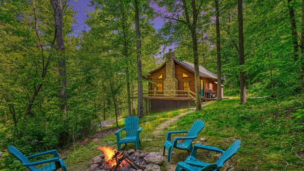 A cabin surrounded by trees with a fire pit and outdoor seating. - Minutes to Caves - 2 KINGS. Hot Tub. Games. Firepit. Close to Everything (Logan)