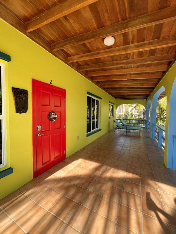 Un couloir avec une porte rouge, un sol carrelé et un plafond en bois.