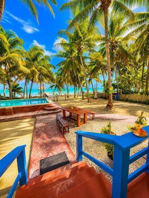 A pool area with palm trees, a wooden deck, and a bench.