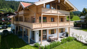 Un chalet in legno a due piani con un balcone, ampie finestre e una zona patio.