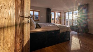 Una camera da letto con una porta in legno, un letto con testiera scura e ampie finestre vista su un paesaggio innevato.