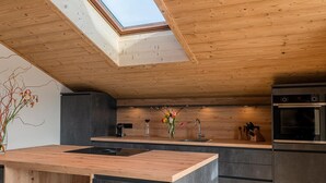 Una cucina moderna con un lucernario, soffitto in legno e isola centrale.