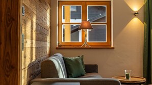 Una habitación acogedora con pared de madera, una ventana con lámpara, un sofá y una mesita con un vaso.